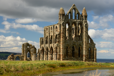 The ruin of Whitby Abbey stands with the sky behind it.
